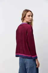 Pullover oversize de punto acanalado en color bordó, con cuello redondo y detalles de franjas en contraste en color azul y fucsia en el cuello, puños y ruedo.