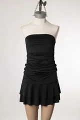 Vestido corto strapless color negro, con corte ajustado en el torso y falda con volados.