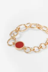 Pulsera de eslabones plateados con cierre de barra y aro, adornada con una piedra circular roja en el centro.
