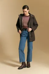 Tapado de paño color marrón oscuro con capucha, cierre frontal oculto con broches, bolsillos aplicados y ajuste interno en la cintura.