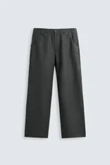 Pantalón de corte relajado confeccionado en tejido de cáñamo color blanco roto. Presenta cintura elástica con cordón interior ajustable, cierre frontal con botones, bolsillos laterales y un bolsillo trasero de plastrón.