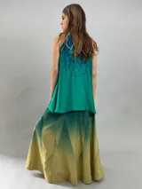 Falda larga de lana con diseño de paneles geométricos y efecto degradado que transiciona de verde esmeralda a tonos amarillentos. Presenta cintura alta, cierre invisible lateral y bolsillos ocultos.