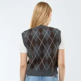 Sweater sin mangas de punto con cuello en V y estampado de rombos en tonos gris y marrón, que incluye una camiseta básica de manga corta en color blanco debajo.