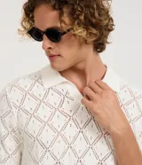Camisa polo de manga corta con diseño de tejido calado tipo crochet y textura de rombos. Presenta cuello polo clásico y terminaciones en tejido acanalado.