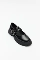 Guillerminas negras de cuero sintético charolado, con plataforma chunky y doble tira ajustable con hebillas metálicas.