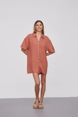 Mono corto color naranja, con cuello camisero, mangas cortas y cierre frontal con botones.