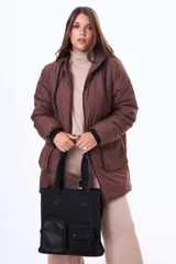 Bolso tipo tote color beige con doble asa superior negra y correa ajustable. Presenta un diseño estructurado con dos bolsillos frontales funcionales, uno con cierre y otro con solapa y broches a presión.