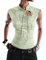 Top verde menta de encaje floral con inspiración oriental, cuello alto, abertura frontal con lazo para anudar, sin mangas y calce ajustado al cuerpo.