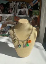 Collar plateado con cadena de eslabones y dijes colgantes con forma de hojas y árbol.