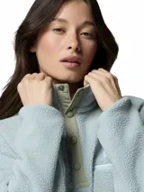 Polar Columbia modelo Helvetia II Cropped, de tejido suave y mullido en color celeste, con cuello alto, cierre frontal parcial con botones a presión y un bolsillo con cierre en el pecho.