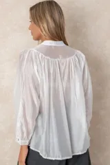 Camisa de organza blanca con cuello mao, diseño de manga larga tipo murciélago y cierre frontal con botones. Presenta un corte holgado y fluido.