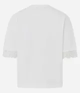 Remera de algodón blanca de corte recto y holgado, con cuello redondo y mangas cortas amplias que presentan una delicada aplicación de encaje en los dobladillos.
