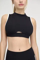 Top deportivo negro con escote alto, abertura en el centro del pecho y ribete blanco en sisas y cuello.