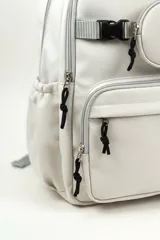 Mochila de poliéster color blanco con múltiples compartimentos con cierre, tiras ajustables y un pequeño monedero frontal con una carita feliz bordada.