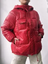 Campera puffer roja con capucha, bolsillos frontales y cordón ajustable en el ruedo.