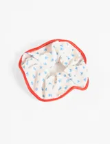Gomita de pelo tipo scrunchie con estampado de flores azules sobre fondo blanco y borde rojo.