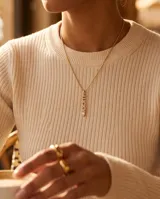 Collar de bronce dorado con cadena fina de eslabones y dije colgante vertical con la palabra "Lucky" incrustada de circonias y una piedra transparente en el extremo.