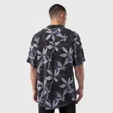 Camisa de manga corta con cuello solapa, confeccionada en viscosa con estampado botánico y tipográfico sobre fondo oscuro. Presenta un corte regular y cierre frontal con botones.