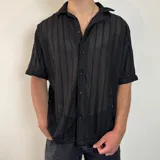 Camisa de manga corta confeccionada en tejido de crochet con diseño de rayas verticales, cuello solapa y cierre frontal con botones.