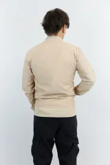 Campera bomber color beige de nylon con cierre frontal y puños y cintura acanalados.