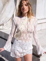 Vestido corto confeccionado en encaje con diseño de mangas largas acampanadas y corte ajustado.