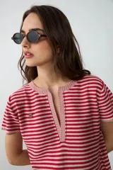 Remera de punto a rayas horizontales en color rojo y crudo, con mangas cortas y escote en V profundo con solapa tipo polo.