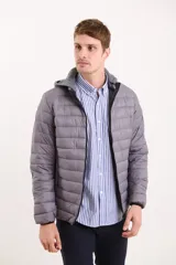 Campera capitoneada color gris con capucha de algodón desmontable y cierre frontal. Cuenta con dos bolsillos exteriores con cierre.