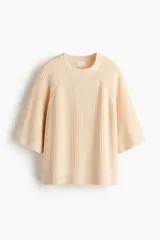 Top de punto acanalado con cuello redondo, mangas al codo de corte raglán y diseño oversized. Presenta terminaciones acanaladas en cuello, puños y bajo.