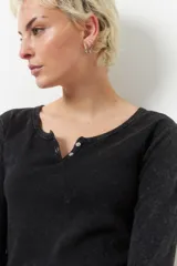 Remera negra de manga larga con cuello base y botones.