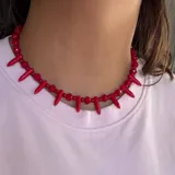 Gargantilla de cuentas facetadas rojas intercaladas con dijes colgantes en forma de púa del mismo color.