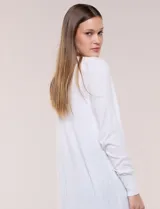 Cardigan largo de punto liviano y suave, de color blanco, con diseño abierto al frente, mangas largas con puños acanalados y bolsillos frontales aplicados.