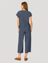 Conjunto de dos piezas compuesto por una remera de manga corta con cuello redondo y frunces laterales ajustables, y un pantalón de corte ancho con cintura elástica y bolsillos laterales.
