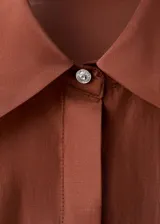 Camisa de manga larga de tejido mezcla lyocell en color marrón cobrizo, con cuello camisero, cierre frontal de botones ocultos y aplicación de strass brillante disperso por toda la prenda.