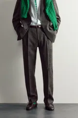 Pantalón de traje regular fit de la colección especial Aaron Levine x Zara, confeccionado en mezcla de lana y lino de color gris. Presenta diseño con pinzas delanteras, bolsillos laterales y traseros de doble vivo con botón, y cierre frontal con cremallera y gancho metálico oculto.