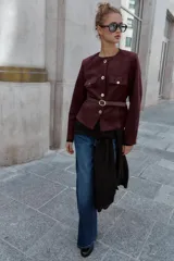 Blazer de cuello redondo y manga larga, confeccionado en tejido efecto ante. Presenta cierre frontal con botones, bolsillos con tapeta en el pecho y cinturón ajustable en la cintura.