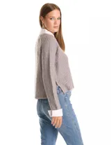 Buzo de tejido de punto acanalado color gris, con escote en V y lentejuelas incrustadas. Presenta un efecto combinado con cuello y puños de camisa blanca asomando por debajo.