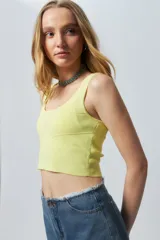 Top negro sin mangas con escote cuadrado, confeccionado en tejido con leve brillo y costuras asimétricas en el frente.