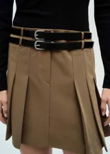 Vestido corto de diseño combinado con cuerpo de tejido de punto negro de cuello alto y manga larga, y falda evasé color tostado con tablas y trabillas. Incluye cinturones decorativos negros con hebillas metálicas.