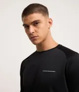 Remera deportiva negra de poliéster con tecnología Dry, cuello redondo, manga larga y estampa lettering en el pecho.