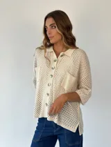 Camisa de punto calado color pistacho con hilos de lurex. Posee cuello camisero, botones frontales, mangas cortas y bolsillos delanteros.