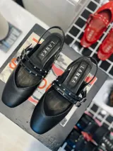 Chatas de cuero negro con punta cuadrada y talón descubierto. Presentan doble pulsera con tachas ajustables y hebilla dorada.