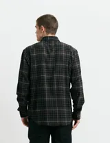Camisa de franela a cuadros con cuello button-down, manga larga y botones de madera. Presenta dos bolsillos tipo parche en el frente con cierre de botón.