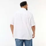Camisa de manga corta color blanco, confeccionada en lino mezclado, con cuello camisero clásico y cierre frontal de botones en contraste.