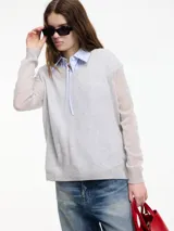 Sweater de punto fino color gris claro, con cuello en V y mangas largas. El tejido parece ser ligeramente transparente o muy liviano.