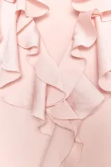 Camisa sin mangas color rosa pálido, con escote en V y volantes que recorren el borde del escote y el centro del delantero.