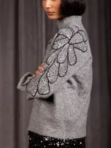 Buzo de cuello alto color gris, de manga larga, con detalle de bordado floral con lentejuelas en el hombro y parte superior de la manga.