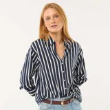 Blusa de corte fluido y holgado con estampado de rayas verticales en azul marino y blanco. Presenta cuello camisero clásico, cierre frontal con botones y mangas largas con puños abotonados.