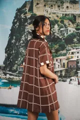 Vestido camisero corto marrón con estampado a cuadros blancos y bolsillo en el pecho.