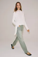 Jeans de tiro bajo y corte recto, confeccionados en denim con estampado de rayas verticales y efecto lavado. Presenta cinco bolsillos, trabillas en la cintura, cierre frontal con cremallera y botón, y un detalle de rotura en la parte delantera.
