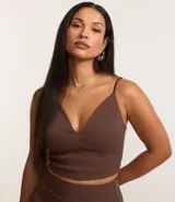 Top cropped color marrón con breteles finos dobles, escote en pico y cierre trasero con cremallera.